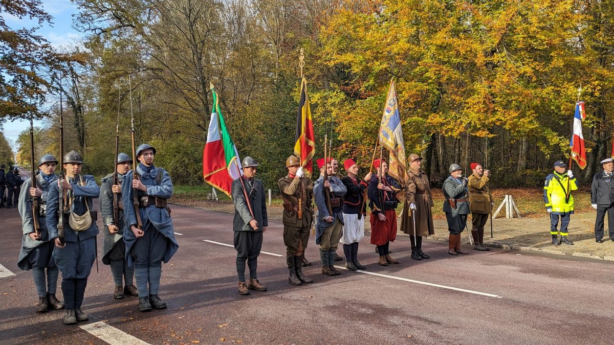 Groupe de participants à la commémoration de l'armistice en costume d'époque, alignés et portant des drapeaux. © Jean-Baptiste Catté